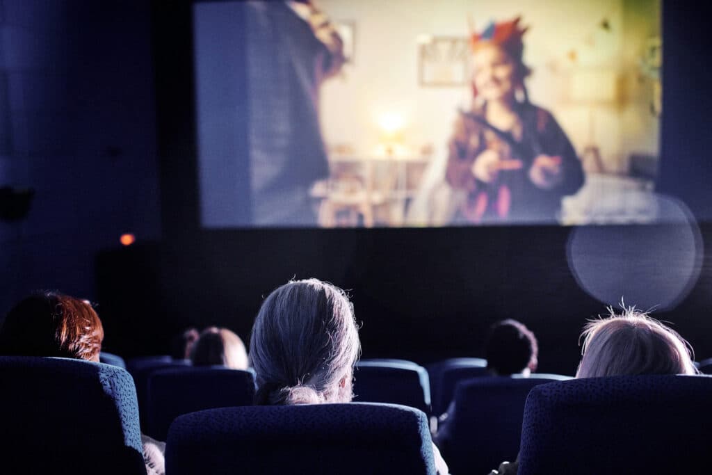 Rear view shot of unrecognizable people spending spare time watching family movie on big screen at cinema